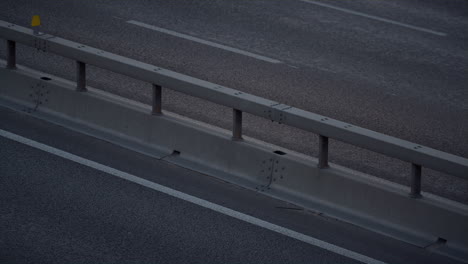 vehicle driving highway evening city drone shot. freeway crash barrier view