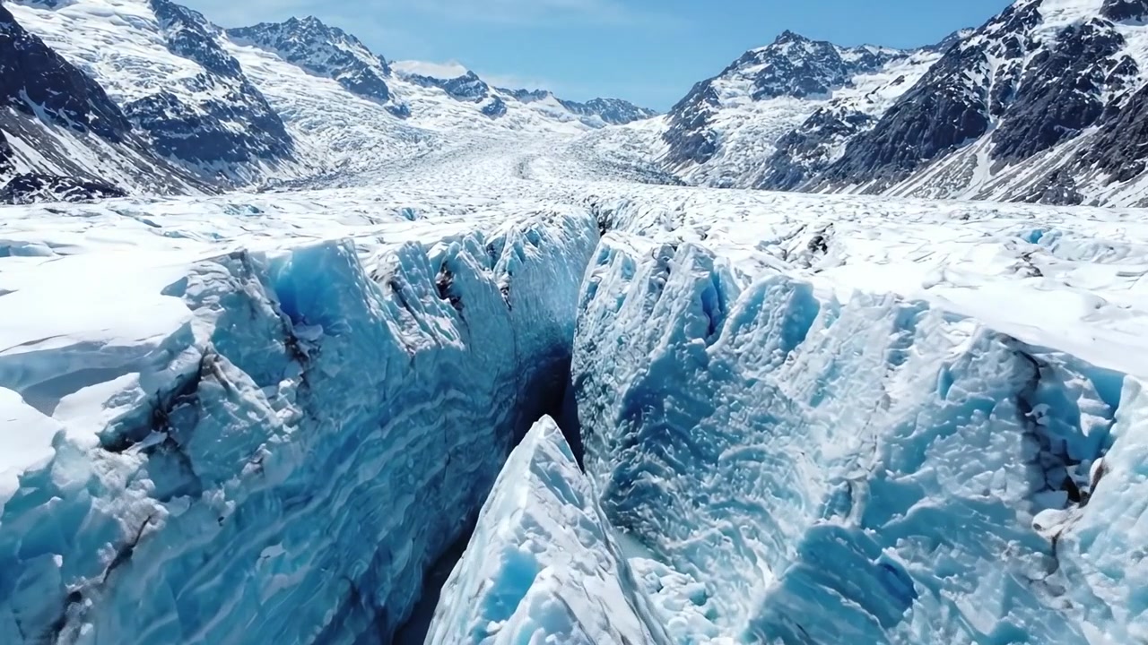 Betagende luftutsikt over en fantastisk isbre: Fengslende isformasjoner midt i majestetiske fjellandskap under en klar blå himmel.