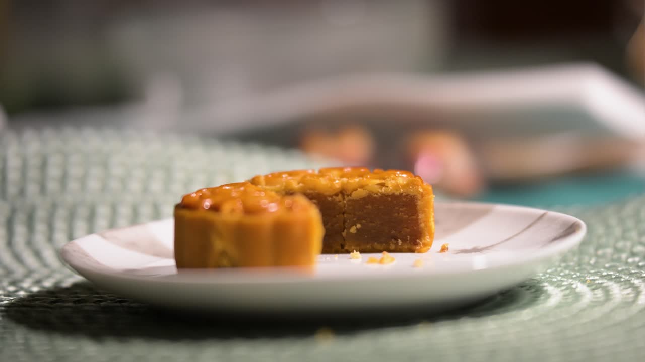 A close-up of a mooncake cut in half, revealing its thick, sweet filling. The golden-brown Chinese pastry, with its intricate pattern, is a popular festival dessert