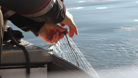 Fisherman's-hands-check-fishing-net-in-water,-slow-motion-shot