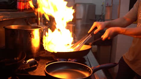 local asian street food culture, professional chef stir frying fresh ingredients with burning flames and aromatic smokes, authentic and traditional hawker centre, handheld close up shot