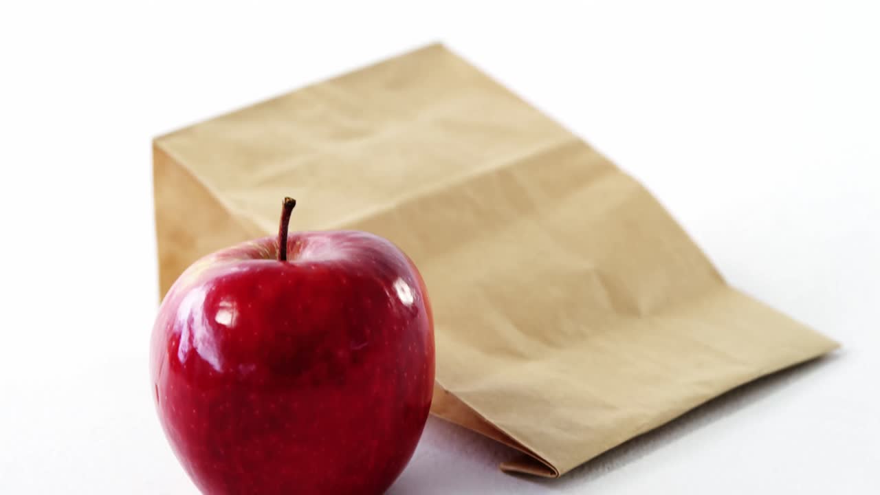 bolsa de papel marrón y manzana sobre fondo blanco
