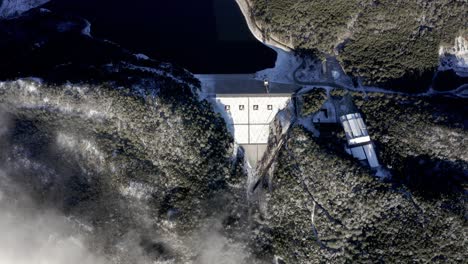 aerial: top down view of hydroelectric dam on snowy cold mountainside