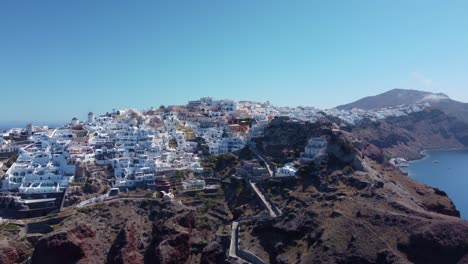 Vuelo-Sobre-Las-Tradicionales-Villas-Blancas-Adosadas-Ini-Village-Oia,-Santorini,-Grecia