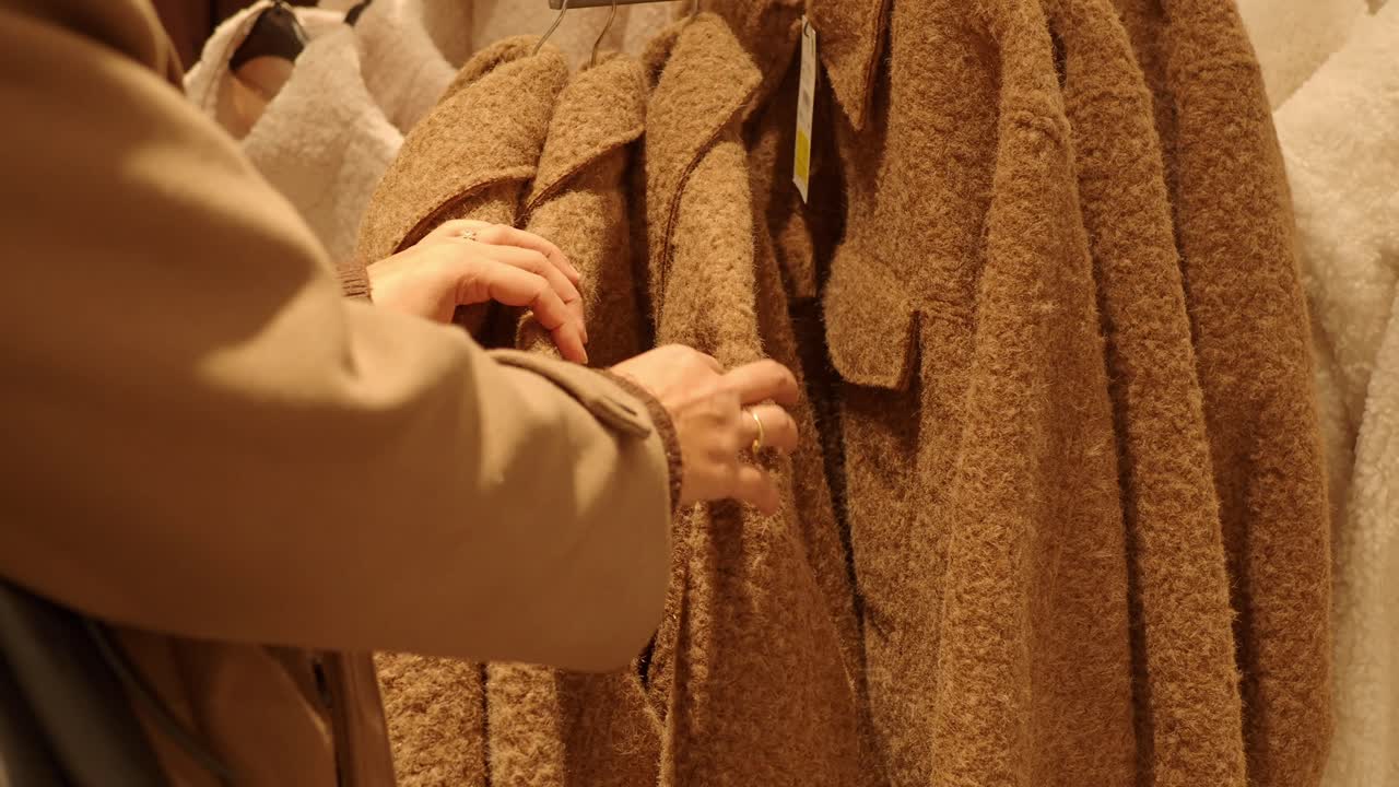 Close-up of Hands Examining Coats in a Retail Shop