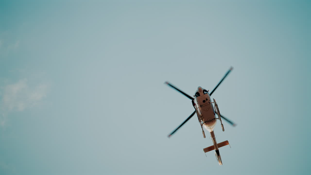 Distant view of a helicopter flying alone against a pale sky