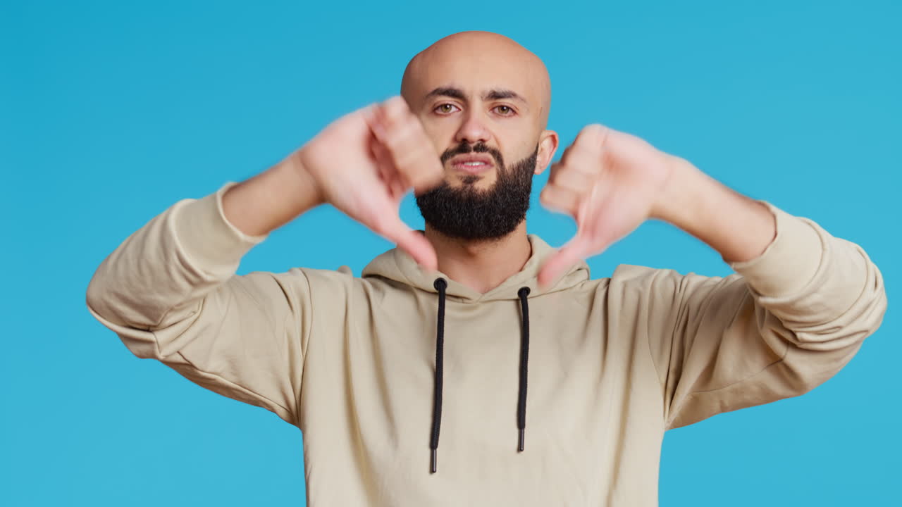 un tipo del medio oriente mostrando el pulgar hacia abajo en la cámara.