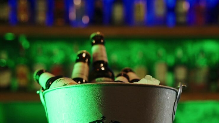 Close-up beer, wine, liquor, champagne bottles in bucket in night club bar pub with neon colorful lights background