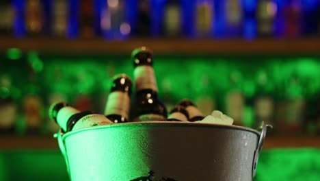 cervezas en primer plano, vino, licor, botellas de champán en un cubo en un bar de club nocturno con luces de neón de fondo