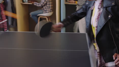 joven mujer afroamericana jugando al ping-pong en la oficina disfrutando de un juego competitivo de tenis de mesa felices colegas divirtiéndose en la pausa para el almuerzo