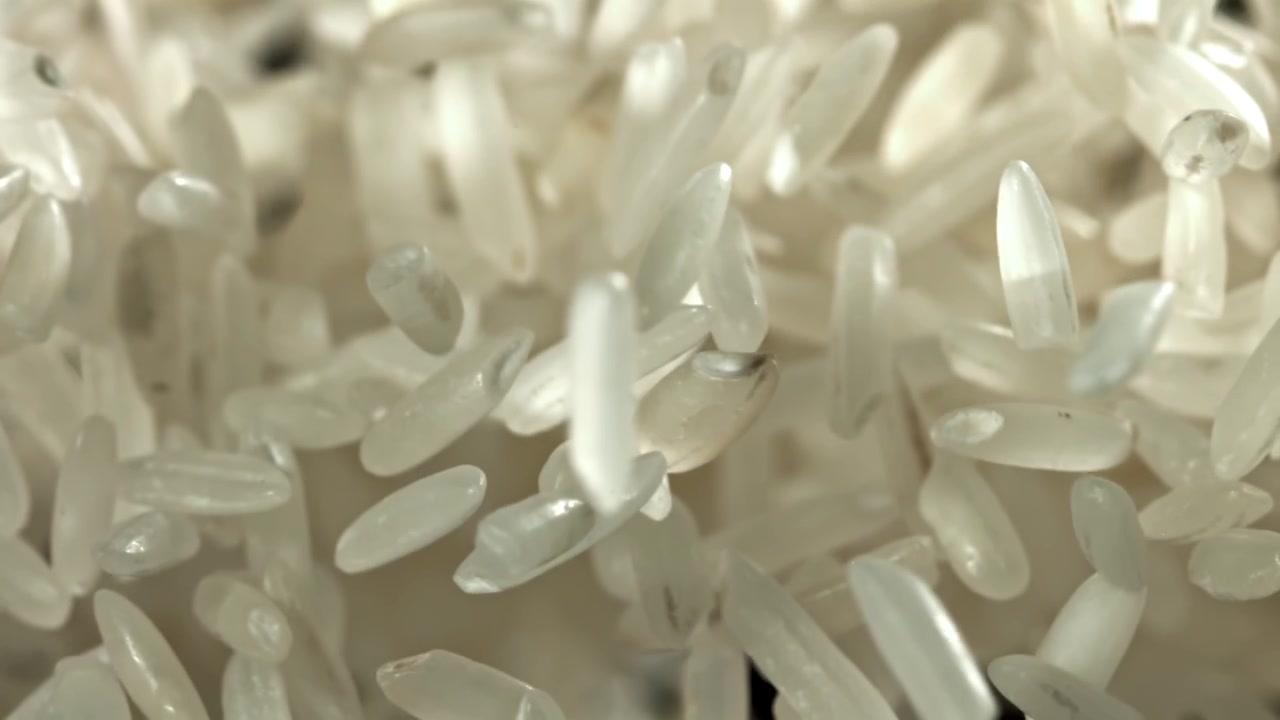 Chicchi di riso bianco che cadono al rallentatore su sfondo nero