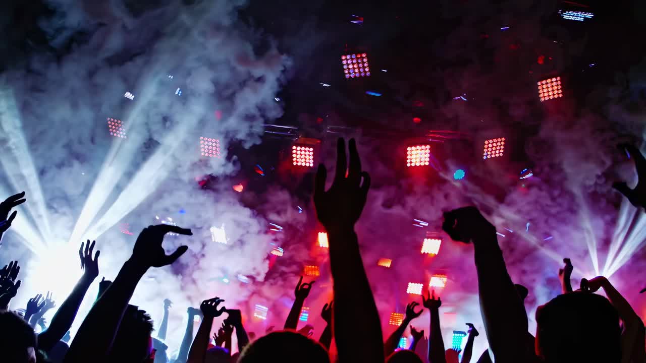 Dynamic concert scene with raised hands and bright lights, captured from a low-angle