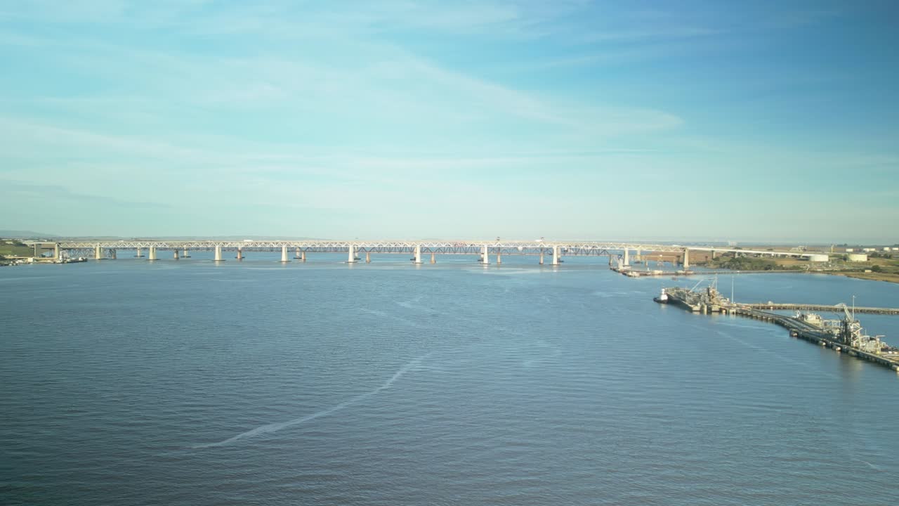 Aerial wide pan across bridges to marine infrastructure along Carquinez Strait Regional Shoreline wetlands in Martinez, California