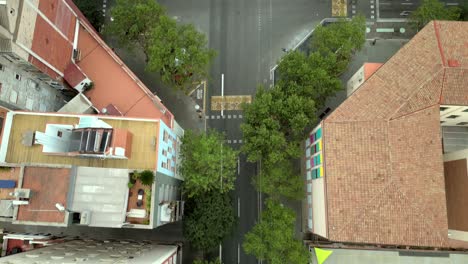 an aerial cinematic shot of a barcelona skyline with the road in between the building and the motor vehicle running on the road