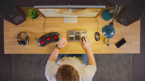 overhead view of male video editor working at computer screen in creative office at night