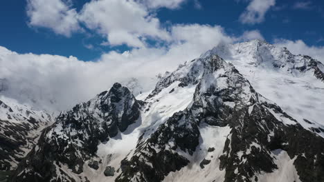 vuelo aéreo a través de nubes montañosas sobre hermosos picos nevados de montañas y glaciares.