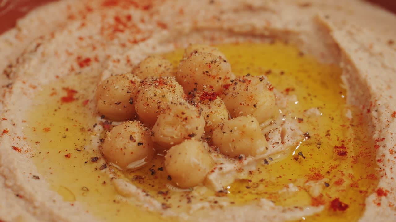 Hummus among fresh vegetables on table close-up. Pouring vegetables slice in hummus. Hummus or fava, a healthy snack of legumes and chickpeas. Kosher healthy vegan food. Lean, vegetarian dish. High quality 4k footage