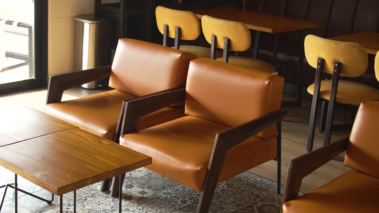 Interno di un caffè in stile Industrial Chic con sedute color senape, divanetti in pelle marrone e divisorio a libreria.