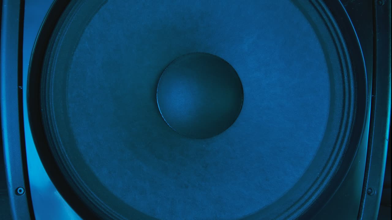 Vibrating bass speaker close up. Black speaker lit by colorful neon club lights vibrates when bass is loud. Concept or dance party. Close up. Slow motion