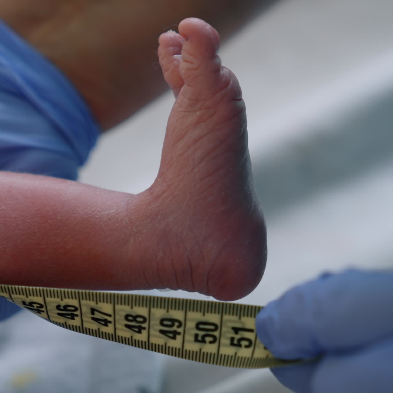 Measuring the newborn's height. Close up of a baby's tiny foot with measuring tape held by the doctor. Close up