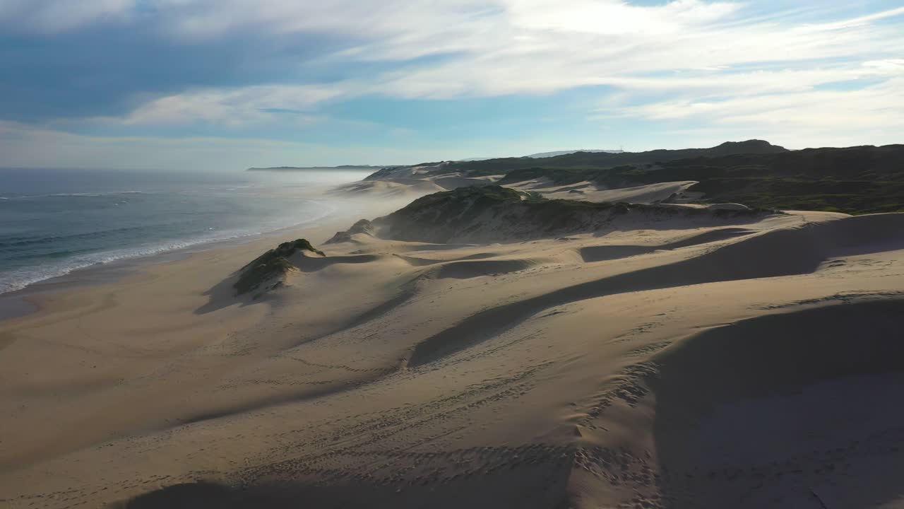 vista de drones volando sobre dunas de arena junto al océano en sudáfrica