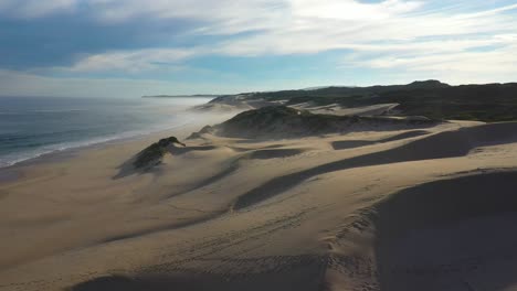 Vista-De-Drones-Volando-Sobre-Dunas-De-Arena-Junto-Al-Océano-En-Sudáfrica