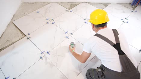 a professional craftsman installs ceramic tiles on the floor  measuring and cutting parts