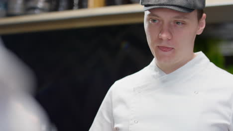 chef using tablet and speaking with colleague in restaurant kitchen