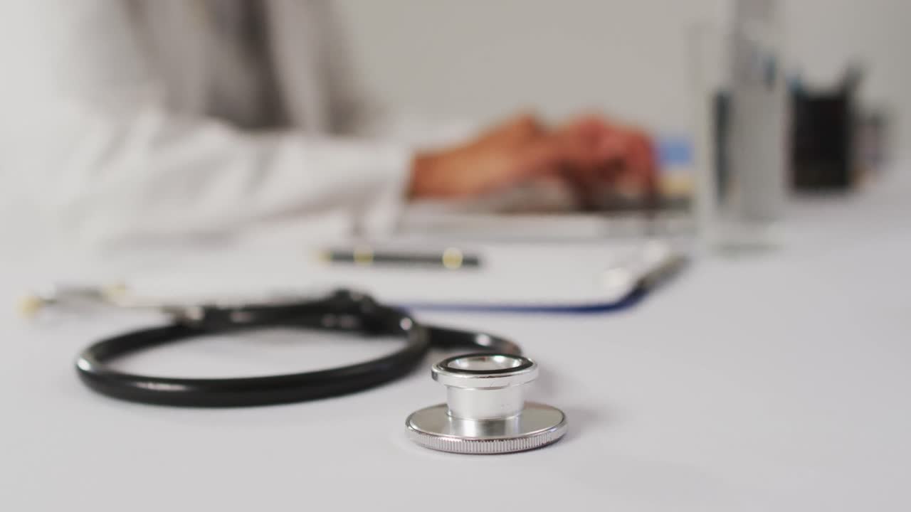video de una doctora biracial usando una computadora portátil sobre un fondo azul