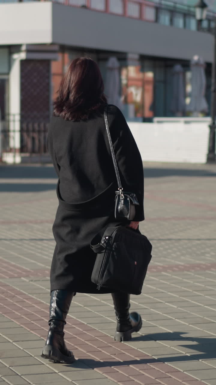 검은 옷을 입은 리모컨 워커가 사무실로 가서 브리프케이스와 드백을 들고, 아침 일찍 빛이 긴 그림자를 던지고, 근대 건축물에 둘러싸인 건물 근처에서 는 남자와 함께