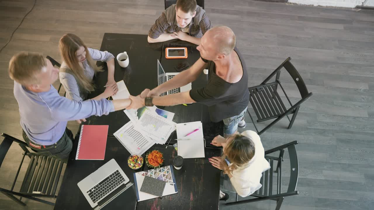 colegas de negocios con éxito terminando el trabajo, estrechando la mano. vista superior en el equipo de compañeros de trabajo colocan sus manos juntas en el centro de un círculo y luego aplauden en una celebración de una reunión exitosa