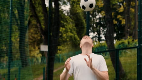 joven jugador de fútbol masculino dirigiendo la pelota en un campo de fútbol callejero 1