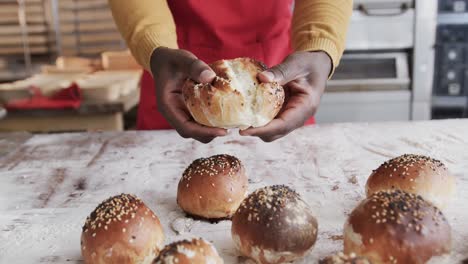 midsection of african american male baker working in bakery kitchen, ripping roll, slow motion