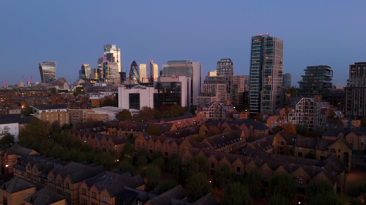 Drone flying over residential homes next to large glass skyscrapers in urban city. Office towers neighbouring housing estate