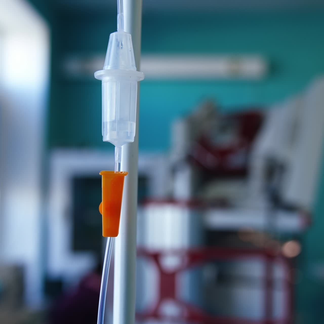 Drop counter and medicines dripping inside the reservoir. Intravenous drip on the stand. Close up. Blurred backdrop