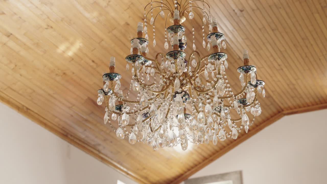 우아 한 크리스탈 들리어 가 은 나무 천장 아래 에 매달려 있다