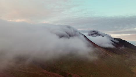 clouds rolling into mountains of borgarfjordur eystri, iceland - aerial drone