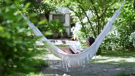 woman reading a book in a hammock in a garden