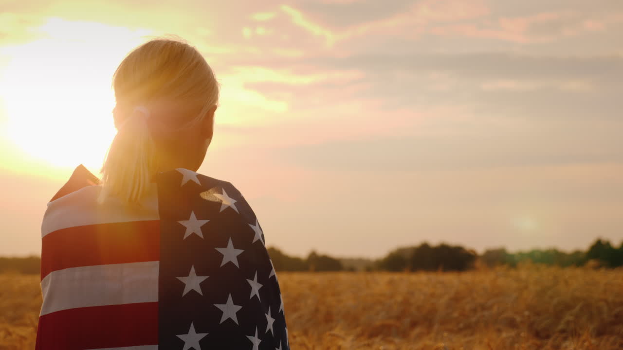 silueta de una granjera en un campo de trigo bandera de estados unidos sobre sus hombros