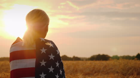 silhouette of a farmer woman in a wheat field usa flag on her shoulders