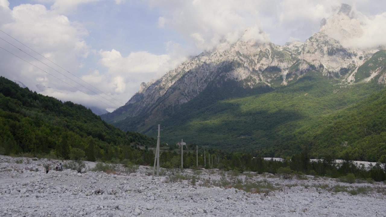 Pendakian kelompok di dasar sungai berbatu Lembah Valbona di Pegunungan Alpen Albania. Alam terbuka Albania.