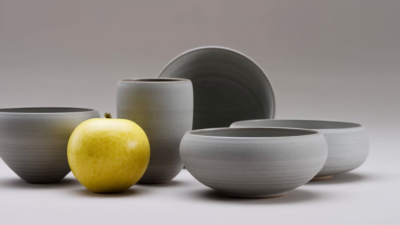 Still Life of Grey Ceramic Tableware with a Yellow Apple