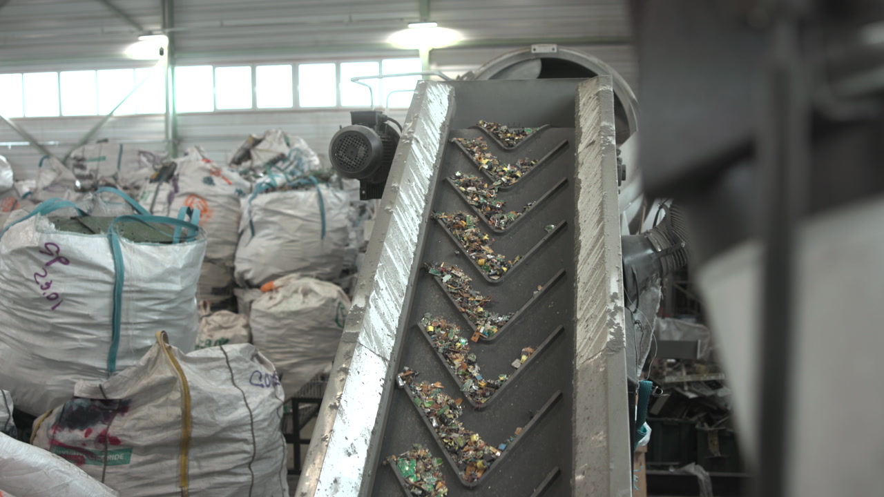 Conveyor Belt Carrying Small Electronic Fragments Up Through Recycling Line, Angled Chevron Paddles Pushing . Media