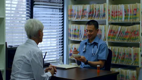Young-Asian-male-doctor-and-senior-patient-interacting-with-each-other-at-clinic-4k