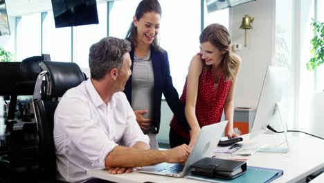 Executives-discussing-over-laptop-in-office