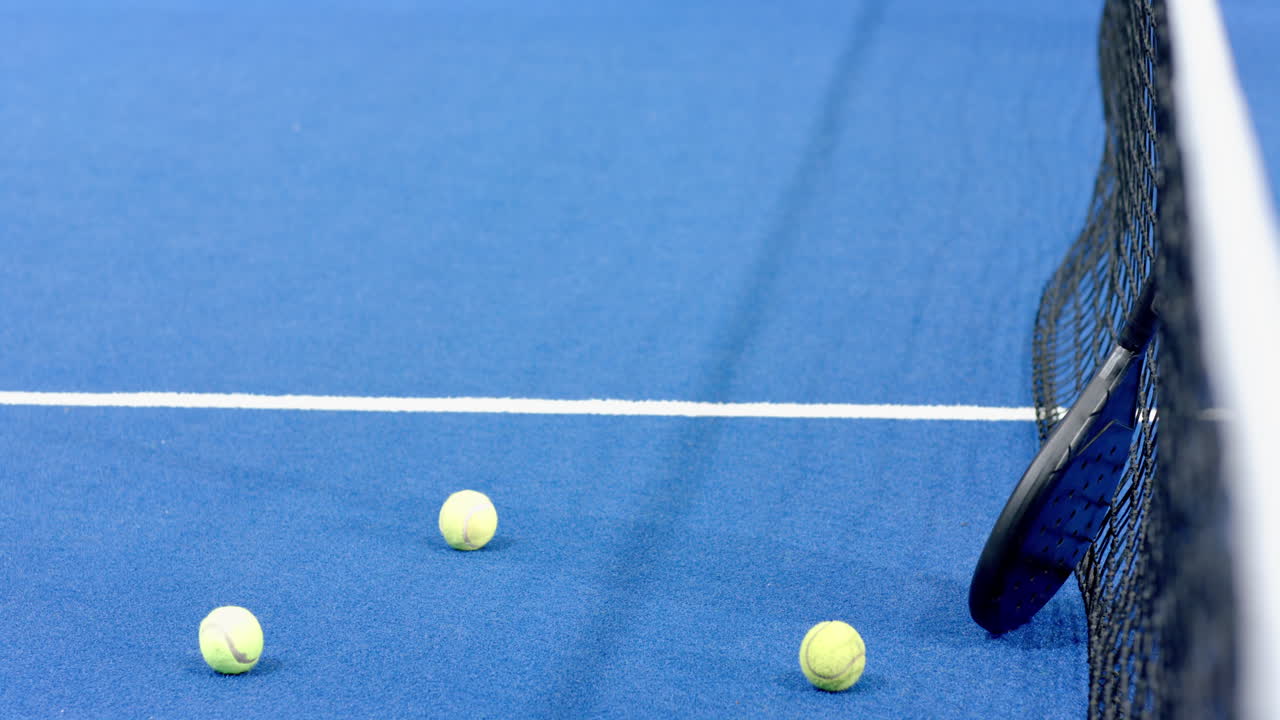 Tennis balls on blue padel indoor court near net, ready for match, copy space