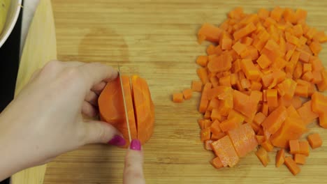 Female-housewife-hands-slicing-carrots-into-pieces-in-the-kitchen