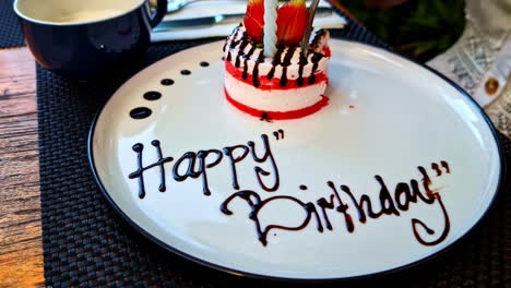 white plate with a birthday dessert and "happy birthday" written in chocolate