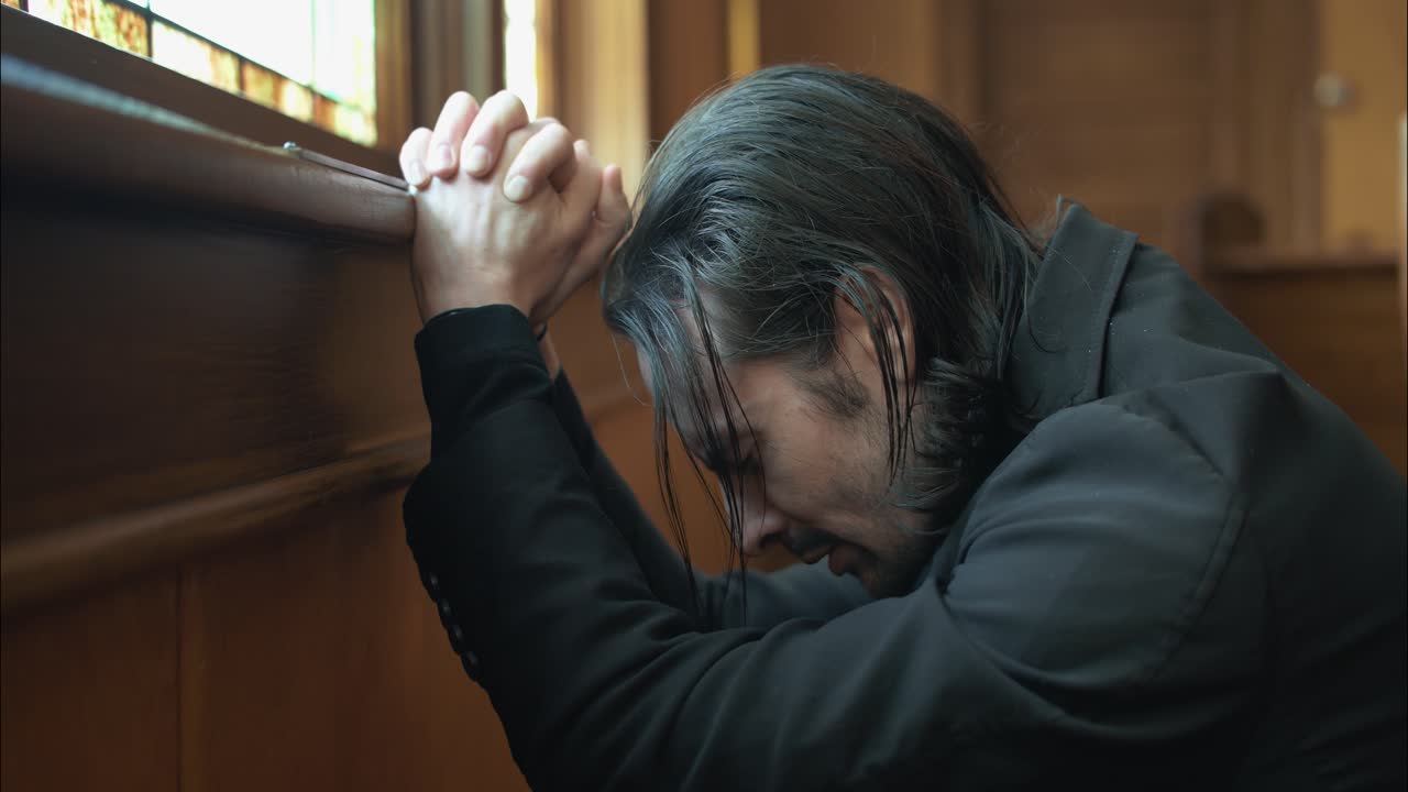 A Christian religious man, priest, preacher, pastor praying inside an old church building