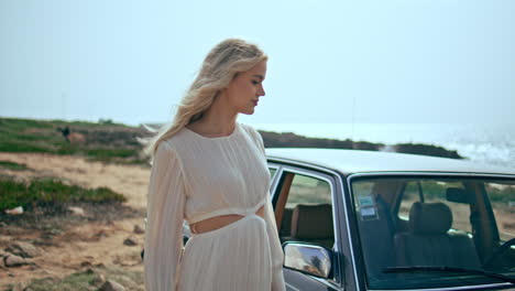 carefree woman walking shore near retro car at summer. traveler enjoying stroll.